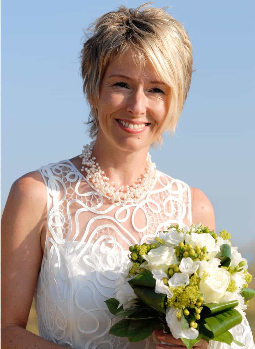 Sabine Piarry in weissem Kleid mit Blumenbouquet an ihrem Hochzeitstag
